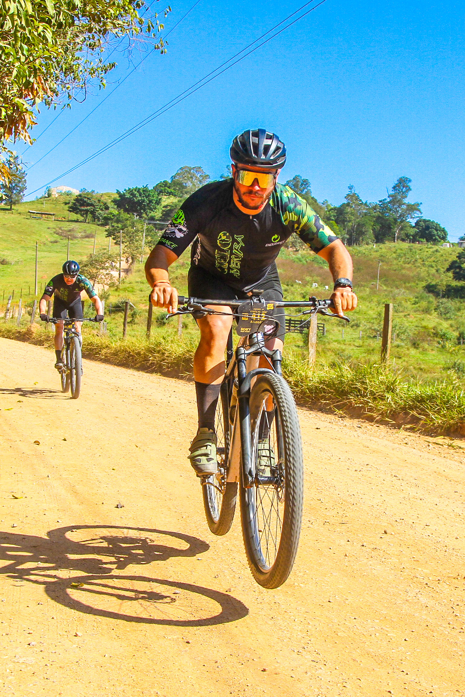 Ciclistas passando por paisagens rurais durante o Tour da Roça em Amparo